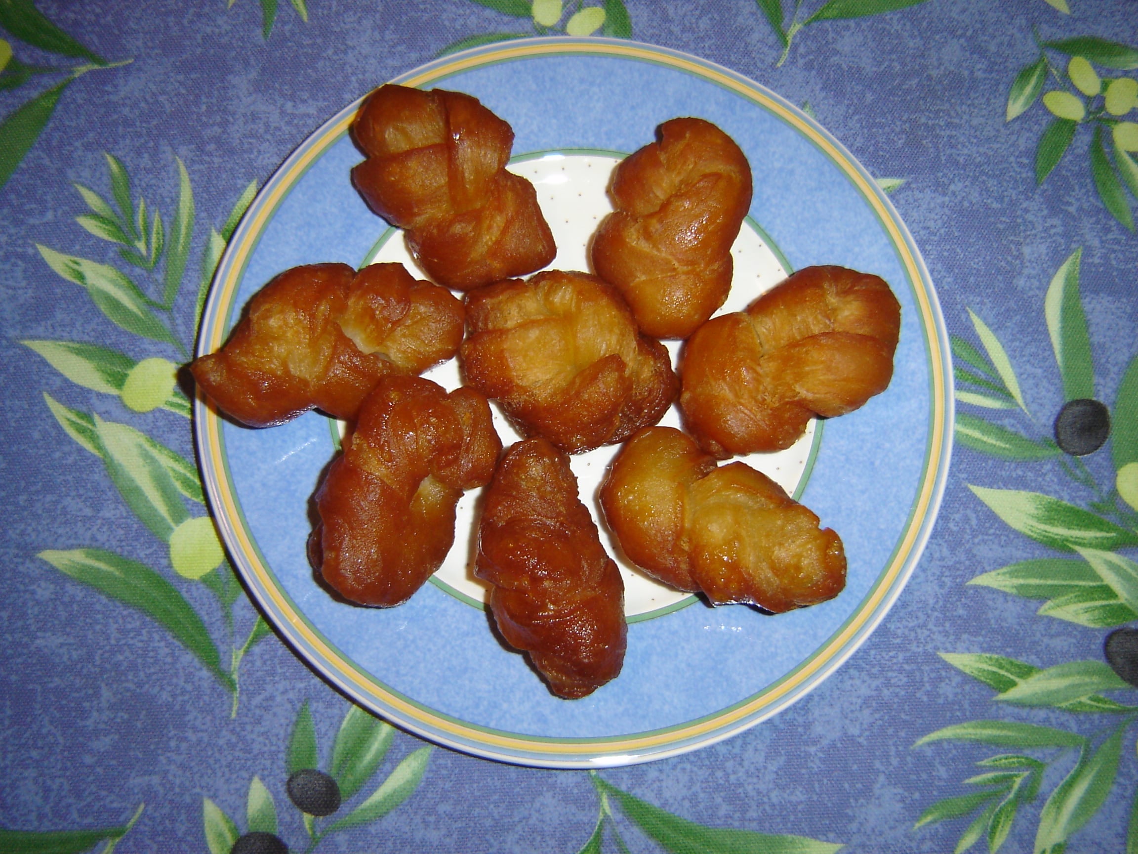 A plate of golden plaited koeksisters, shiny with syrup
