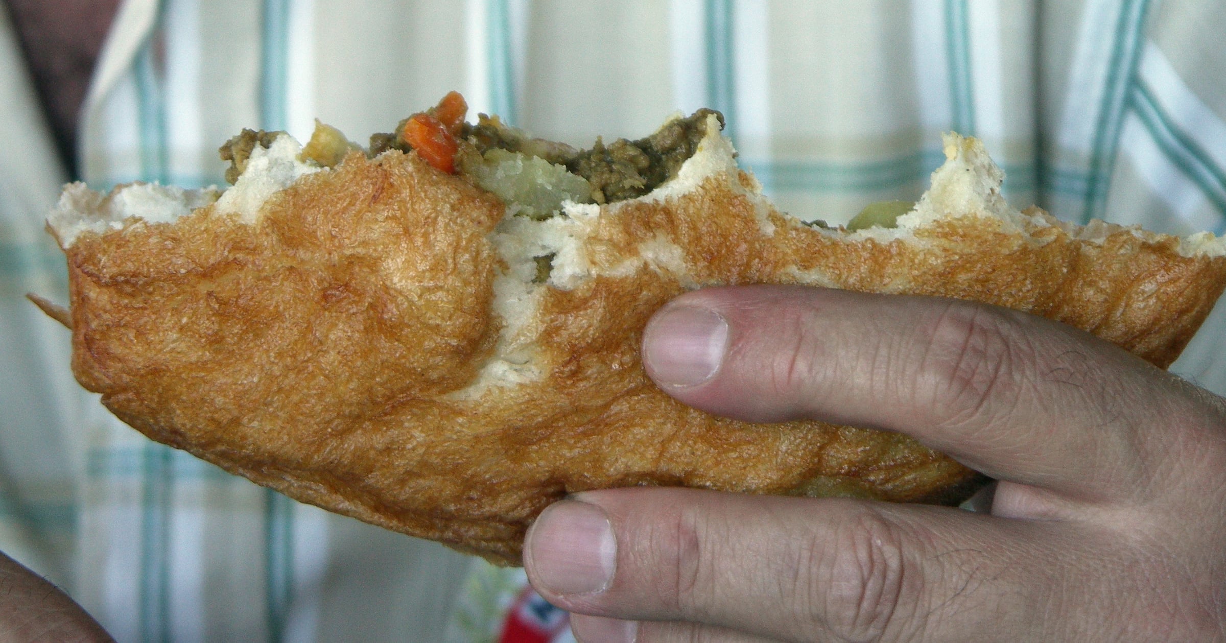 A vetkoek split open and filled with savoury mince